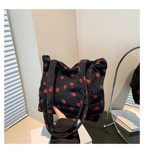 Detail of black corduroy tote bag with red strawberry pattern in a home setting