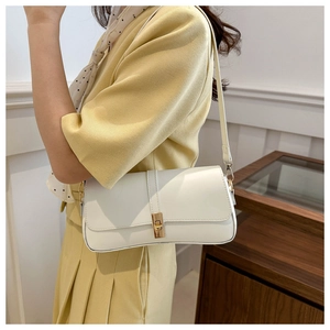 Sac à épaule chic en similicuir blanc avec boucle dorée porté par un mannequin