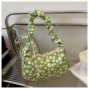 Detail of floral shoulder bag with ruched handle and bow on a textured silver chair