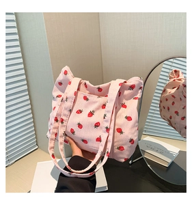 Detail of pink corduroy tote bag with red strawberry pattern and dual handles