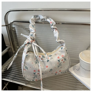Detail of floral canvas bag featuring a ruched handle and side bow decorative detail