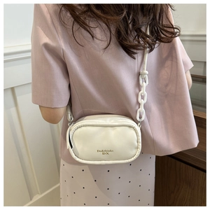Detail of white PU leather crossbody bag with chunky chain strap and gold logo