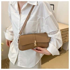 Détail d'un sac sous le bras en cuir marron avec fermoir doré sur un mannequin