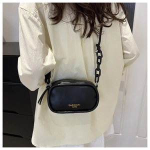 Detail of black PU leather crossbody bag with gold logo and thick chain shoulder strap