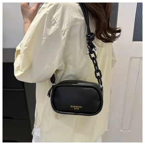 Detail of minimalist black leather crossbody bag with knot strap and chain decoration