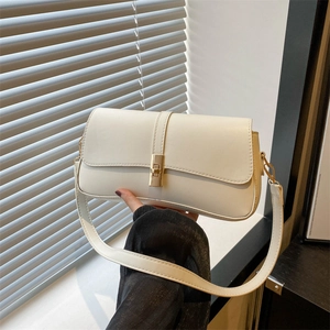 Sac sous le bras minimaliste en cuir blanc crème avec fermoir doré sur fond de persiennes