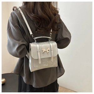 Silver metallic mini backpack with large butterfly clasp worn by model on back