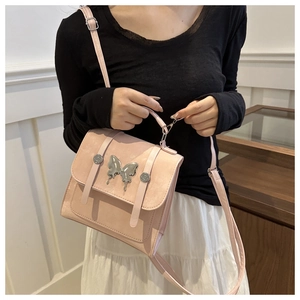 Detail of light pink crossbody bag featuring a silver butterfly buckle and matte texture