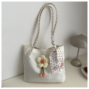 Close-up of white tote bag featuring 3D fabric flower and silk scarf detail