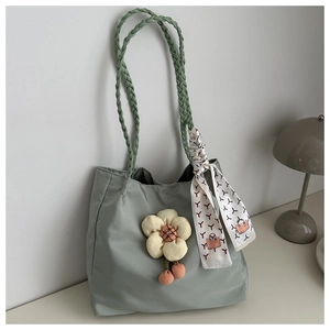 Detail of light green nylon tote with woven handles, silk scarf and flower pendant