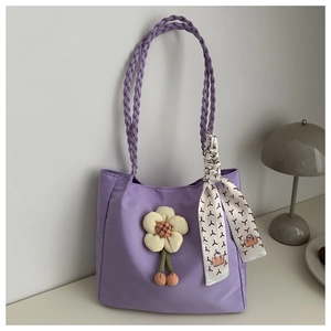 Detail of lavender tote bag with woven handles, fabric flower charm and decorative scarf
