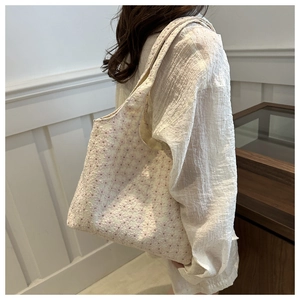 Detail showing the floral lace embroidery and soft texture of a pink floral tote bag
