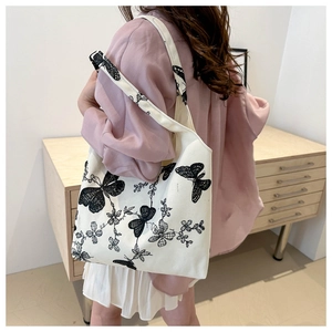 Detail of canvas tote bag featuring black butterfly and botanical floral embroidery