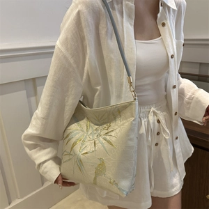 Elegant white embroidered tote bag with gold bamboo and blue bird patterns on silk texture