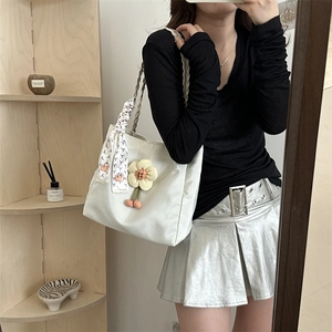 White nylon tote bag with floral pendant and silk scarf charm shown on shoulder