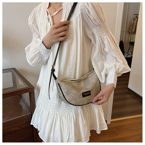 Detail of minimalist beige dumpling bag with black piping and New York fashion logo