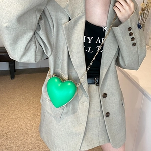 Fashionable green heart-shaped crossbody bag with gold chain strap on a model