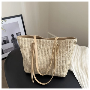 Close-up of beige straw tote bag with woven texture and premium leather straps