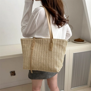 Minimalist beige woven tote bag with brown leather straps shown in a lifestyle setting