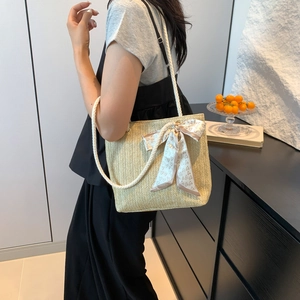 Large beige straw tote bag with heart bow and rope straps shown in a modern interior