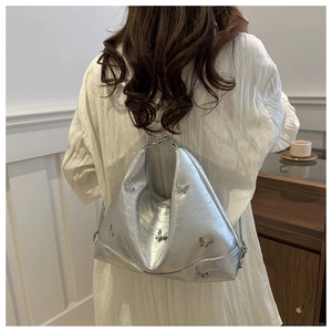 Detail of silver tote bag with crocodile texture and 3D metal butterfly decorations