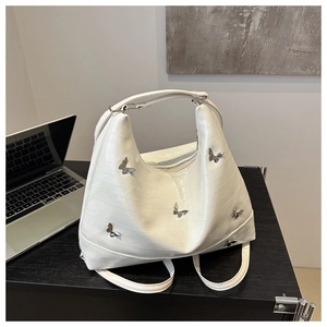 Detailed view of white crocodile texture tote bag with silver butterfly metal charms