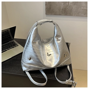 Detailed view of metallic silver pleated tote bag with 3D butterfly embellishments