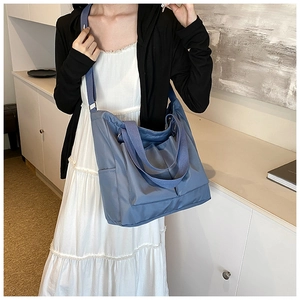Lifestyle view of a large blue tote bag worn by a model in a minimal setting