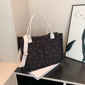 Corduroy tote bag with red strawberry pattern, white handles and shoulder strap