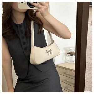 Détail du sac sous le bras blanc crème avec boucle noeud argentée en selfie miroir