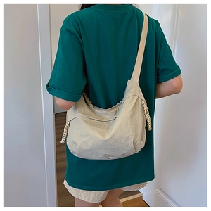 Beige nylon crossbody bag with wide shoulder strap shown on model in daily casual scene