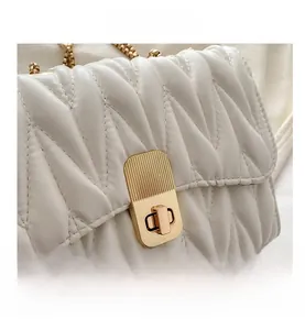 Détail du sac matelassé blanc avec coutures en V et fermoir rectangulaire doré chic