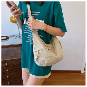Detail of a beige nylon crescent crossbody bag with braided rope and pleats
