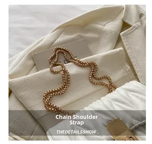 Détail d'un sac matelassé blanc avec fermoir en métal doré et bandoulière chaîne épaisse