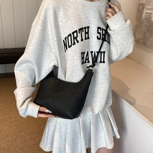 Sac hobo minimaliste en cuir noir pour femme porté par un mannequin avec fine bandoulière