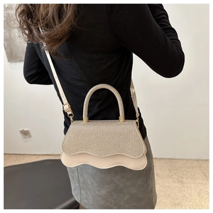 Dettaglio della mini borsa beige con paillettes, patta a onde e manico dorato