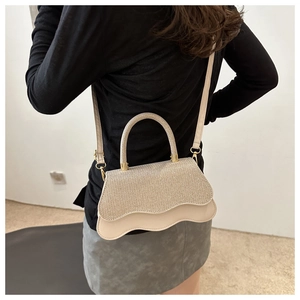 Dettaglio della patta glitter oro champagne e pelle bianco panna ondulata sulla borsa