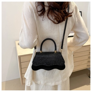 Dettaglio mini borsa in paillettes nere con base a onde e dettagli dorati su modella