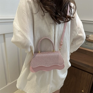 Borsa a mano rosa con strass, base ondulata e dettagli dorati, portata a tracolla
