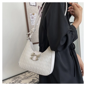 Detail of white woven leather crescent bag with silver bow buckle worn on shoulder