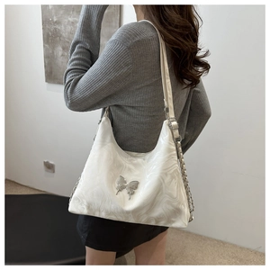 Detail of white marble print shoulder bag with silver butterfly and metal chain strap