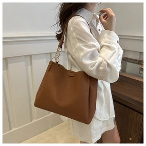 Close-up of caramel leather tote bag with pebble texture and gold chain shoulder strap