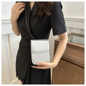 Sac bandoulière argenté pour téléphone avec fine chaîne porté par un mannequin