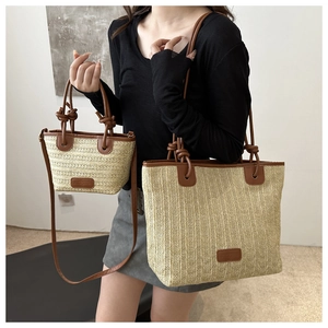 Close-up of straw tote bag showing beige woven texture and brown leather strap knots