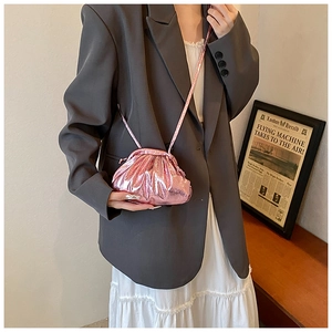 Détail du sac à main plissé rose métallisé porté avec une bandoulière sur un blazer gris