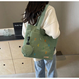 Detail of green canvas tote bag with colorful embroidery and matching round coin purse