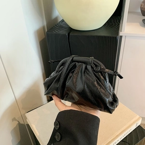 Detail of glossy black leather dumpling bag with soft pleats and drawstring closure