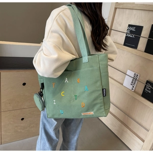 Détail du sac fourre-tout en toile verte avec broderies colorées et petit porte-monnaie