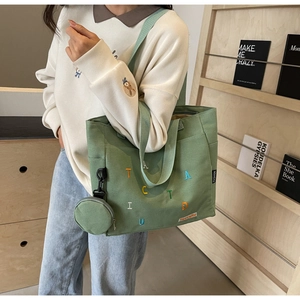 Close-up of green canvas tote bag with colorful embroidery and round coin purse