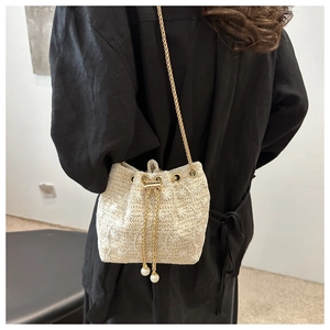 Detail of cream woven bucket bag with 3D floral embroidery and pearl drawstring charms